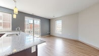 Located in the heart of downtown Columbus, Ohio, this 2-bedroom, 1-bathroom residence offers a well-designed single-floor layout. The open-concept kitchen and living area serves as the centerpiece of the home, bathed in natural light from large windows and a sliding glass door that opens to a private balcony with city views. The kitchen is outfitted with rich dark wood cabinetry, granite countertops, stainless steel appliances including a refrigerator, range, and microwave, and a peninsula with pendant lighting — ideal for both cooking and casual dining.

The living area features light hardwood-style flooring and a neutral color palette with a charcoal accent wall, creating a modern yet welcoming atmosphere. A well-lit hallway connects the living spaces to the two bedrooms, both of which are carpeted and receive ample natural light through large windows. The generously sized primary bedroom offers a comfortable retreat, while the second bedroom is equally bright. The full bathroom is clean and functional, featuring a tiled soaking tub, hardwood-style flooring, and a granite-topped vanity. Additional spaces include a laundry area, utility room, two closets, and an entrance — rounding out a complete and practical urban living experience.