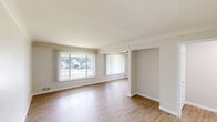 Located at 5965 Evergreen Rd in Dearborn Heights, Michigan, this 2-bedroom, 1-bathroom unit offers a well-designed single-floor layout with a clean, modern aesthetic throughout. Light wood-tone flooring runs continuously across all rooms, creating a cohesive and bright atmosphere.

The open living room is generously proportioned, featuring large windows with vertical blinds that allow abundant natural light and views of the surrounding neighborhood. A ceiling fan adds comfort to the space.

The kitchen is efficiently laid out with crisp white shaker cabinetry accented by gold hardware, dark granite countertops, a stainless steel sink, and a full suite of stainless steel appliances including a gas range, over-the-range microwave, and refrigerator. A skylight provides additional natural illumination.

Both bedrooms are comfortable and well-lit, each equipped with ceiling fans with light fixtures and windows dressed with vertical blinds. The primary bedroom includes a built-in closet, and both rooms connect conveniently via a central hallway.

The bathroom is finished with large-format marble-look tile on both the floors and tub surround, complemented by a white vanity with gold hardware and dark countertop, offering a polished, updated look throughout.