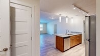 This single-floor unit in Ellicott City, Maryland, offers a thoughtfully arranged layout with three bedrooms, two bathrooms, a kitchen, living room, laundry room, and hallway. Light-toned luxury vinyl plank flooring runs throughout the main living areas, complemented by neutral warm beige walls that create a clean, cohesive aesthetic.

The kitchen is a standout feature, equipped with warm wood cabinetry, granite countertops, a subway tile backsplash, and stainless steel appliances including a refrigerator, range, and microwave. A peninsula with pendant lighting and an integrated sink overlooks the open living area, which receives natural light through large windows and offers access to an outdoor balcony via a glass-panel door.

The bedrooms feature plush wall-to-wall carpeting and large windows with blinds, filling each room with natural light. The primary bedroom offers a comfortable, well-proportioned retreat. Both bathrooms are finished with wood vanities and stone-look countertops, with one featuring a tub-shower combination. The dedicated laundry room accommodates a full-size washer and dryer alongside utility storage, adding everyday convenience to this well-appointed home.
