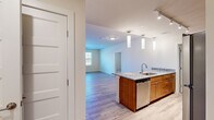 This single-floor unit in Ellicott City, Maryland, offers a thoughtfully arranged layout with three bedrooms, two bathrooms, a kitchen, living room, laundry room, and hallway. Light-toned luxury vinyl plank flooring runs throughout the main living areas, complemented by neutral warm beige walls that create a clean, cohesive aesthetic.

The kitchen is a standout feature, equipped with warm wood cabinetry, granite countertops, a subway tile backsplash, and stainless steel appliances including a refrigerator, range, and microwave. A peninsula with pendant lighting and an integrated sink overlooks the open living area, which receives natural light through large windows and offers access to an outdoor balcony via a glass-panel door.

The bedrooms feature plush wall-to-wall carpeting and large windows with blinds, filling each room with natural light. The primary bedroom offers a comfortable, well-proportioned retreat. Both bathrooms are finished with wood vanities and stone-look countertops, with one featuring a tub-shower combination. The dedicated laundry room accommodates a full-size washer and dryer alongside utility storage, adding everyday convenience to this well-appointed home.