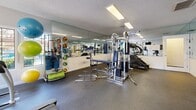 This fitness center at 4201 W Rochelle Ave in Las Vegas, NV is a fully equipped exercise facility designed to support a well-rounded workout routine. The single-room space is thoughtfully organized to maximize its footprint, with equipment arranged efficiently throughout.

The strength training area features a multi-station cable machine, a flat weight bench, and a tiered dumbbell rack stocked with a wide range of free weights. Full-length mirrors line the walls, visually expanding the space and allowing users to monitor their form during exercise. A variety of accessories, including resistance bands, medicine balls, and stability balls, are also available for functional training.

The cardio section includes a treadmill, a stationary recumbent bike, and an elliptical trainer, all positioned near a window that offers a view of the outdoor surroundings, bringing in natural light and a sense of openness. A wall-mounted flat-screen television is conveniently placed for entertainment during cardio sessions.

The room features durable rubber flooring suitable for heavy equipment and high-impact use. Recessed fluorescent lighting provides bright, even illumination throughout. A textured ceiling and clean white walls give the space a crisp, practical aesthetic. Informational postings near the entrance provide facility guidelines for users.
