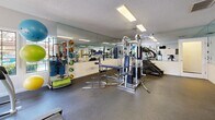 This fitness center at 4201 W Rochelle Ave in Las Vegas, NV is a fully equipped exercise facility designed to support a well-rounded workout routine. The single-room space is thoughtfully organized to maximize its footprint, with equipment arranged efficiently throughout.

The strength training area features a multi-station cable machine, a flat weight bench, and a tiered dumbbell rack stocked with a wide range of free weights. Full-length mirrors line the walls, visually expanding the space and allowing users to monitor their form during exercise. A variety of accessories, including resistance bands, medicine balls, and stability balls, are also available for functional training.

The cardio section includes a treadmill, a stationary recumbent bike, and an elliptical trainer, all positioned near a window that offers a view of the outdoor surroundings, bringing in natural light and a sense of openness. A wall-mounted flat-screen television is conveniently placed for entertainment during cardio sessions.

The room features durable rubber flooring suitable for heavy equipment and high-impact use. Recessed fluorescent lighting provides bright, even illumination throughout. A textured ceiling and clean white walls give the space a crisp, practical aesthetic. Informational postings near the entrance provide facility guidelines for users.