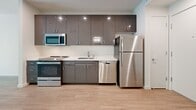 This studio in West Sacramento, California offers a well-designed, open-concept layout that efficiently combines the kitchen and living areas into a single cohesive space. Light-toned hardwood-style flooring runs throughout, lending a clean and modern aesthetic that ties the entire unit together.

The kitchen is a standout feature, equipped with a full suite of stainless steel appliances including a refrigerator, range, microwave, and dishwasher. Sleek, high-gloss gray cabinetry extends to the ceiling, maximizing storage, while white countertops provide a bright contrast. Recessed lighting illuminates the workspace effectively.

The living area is open and airy, filled with natural light from a large sliding glass door that offers outdoor views and access to an exterior space, complemented by an additional window. The clean white walls and neutral tones create a calm, versatile backdrop.

The bathroom is finished with a full tub-shower combination, modern chrome fixtures, and consistent hardwood-style flooring, maintaining the cohesive design language found throughout the unit. A dedicated closet provides practical storage solutions.

Overall, this studio presents a modern, functional, and light-filled living space well-suited for those seeking a compact yet thoughtfully appointed home in West Sacramento.