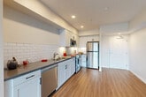Located at 7750 Bolsa Ave in Midway City, CA, this thoughtfully designed 1-bedroom, 2-bathroom unit offers a clean, modern aesthetic throughout its efficiently utilized single-floor layout. Warm wood-look flooring runs continuously across all living areas, creating a cohesive and inviting atmosphere.

The open-concept kitchen is a standout feature, showcasing white shaker cabinetry, a classic white subway tile backsplash, dark gray countertops, and a full suite of stainless steel appliances including a refrigerator, gas range, microwave, and dishwasher. Recessed lighting illuminates the space with a bright, contemporary feel. The kitchen flows seamlessly into the living area, which benefits from abundant natural light streaming through a full sliding glass door that opens to a private balcony with outdoor views.

The spacious primary bedroom features a large window overlooking greenery, a mirrored sliding-door closet, and continues the warm flooring aesthetic. Both bathrooms are finished with white cabinetry, dark countertops, and glass-enclosed shower stalls. Clean lines and neutral tones are maintained throughout, contributing to the unit's modern and functional character.