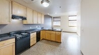 Located at 46 Fourth St E in downtown Saint Paul, MN, this one-bedroom, one-bathroom unit offers a thoughtfully arranged single-floor layout. Terrazzo flooring flows consistently throughout every room, lending a clean, durable, and cohesive aesthetic to the entire space.

The open-concept kitchen and living area forms the heart of the unit. The kitchen is outfitted with light maple cabinetry, dark granite-style countertops, black appliances including a refrigerator, range, and dishwasher, and a peninsula with a sink that opens toward the living area. Natural light enters through multiple windows dressed with horizontal blinds, brightening the combined space.

The bedroom is a calm, private retreat featuring its own window with blinds that allow for natural light and street views. Two closets provide ample storage, and light maple interior doors with chrome hardware are consistent throughout the unit, reinforcing a cohesive design language.

The bathroom is straightforward and functional, featuring a full soaking tub with a shower, a toilet, and a vanity with dark countertops that complement the kitchen's finishes. An in-unit laundry area adds everyday convenience. The entry door is a solid, heavy-duty design consistent with a secure urban residential building. Overall, the unit presents a practical and well-organized living space in the heart of Saint Paul.