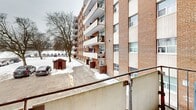 Located at 230 Nipigon St in Oshawa, Ontario, this one-bedroom, one-bathroom unit is situated on the second floor of a mid-rise brick building. The unit offers a practical and well-organized layout, beginning with a welcoming entrance that leads through a hallway connecting all principal areas of the home.

The galley-style kitchen is neatly appointed with white cabinetry extending to the ceiling on both sides, a light marble-effect countertop, a stainless steel sink, and white appliances including an electric range and refrigerator. Tile flooring runs throughout the kitchen, transitioning into the characteristic parquet wood flooring found across the rest of the unit.

The living room and adjoining dining area are bright and open, benefiting from natural light and featuring the same warm parquet flooring and a decorative textured ceiling. The bedroom is a comfortable size, offering a window with views of the surrounding building exterior, a built-in sliding door closet, and the same parquet flooring. In total, the unit includes three closets, providing generous storage throughout.

The bathroom is clean and functional, featuring a full-size soaker tub with an overhead shower and white tile surround. A private balcony off the unit overlooks the parking area and a backdrop of mature trees, offering an outdoor retreat. Baseboard heating is present throughout the unit.