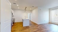 This well-designed 2-bedroom, 1-bathroom unit in Fort Collins, Colorado offers a clean, contemporary layout across a single floor. The open-concept kitchen and living area serves as the heart of the home, anchored by a central island with a built-in sink and sleek pendant lighting overhead. The kitchen is outfitted with crisp white cabinetry, white quartz-style countertops, subway tile backsplash, and a full suite of stainless steel appliances including a side-by-side refrigerator, electric range, and over-the-range microwave. Warm hardwood-style flooring flows throughout the main living areas, adding a welcoming, modern character. The primary bedroom is generously sized and connects to a walk-in closet with built-in shelving and hanging rods. The second bedroom features soft carpeting and a window that brings in natural light. A shared full bathroom includes a tub-shower combination with clean white finishes and hardwood-style flooring. Additional storage is provided by two closets throughout the unit. A connecting hallway ties the layout together efficiently. The bright, neutral color palette and recessed lighting throughout create a fresh, move-in-ready atmosphere.