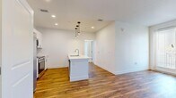 This well-designed 2-bedroom, 1-bathroom unit in Fort Collins, Colorado offers a clean, contemporary layout across a single floor. The open-concept kitchen and living area serves as the heart of the home, anchored by a central island with a built-in sink and sleek pendant lighting overhead. The kitchen is outfitted with crisp white cabinetry, white quartz-style countertops, subway tile backsplash, and a full suite of stainless steel appliances including a side-by-side refrigerator, electric range, and over-the-range microwave. Warm hardwood-style flooring flows throughout the main living areas, adding a welcoming, modern character. The primary bedroom is generously sized and connects to a walk-in closet with built-in shelving and hanging rods. The second bedroom features soft carpeting and a window that brings in natural light. A shared full bathroom includes a tub-shower combination with clean white finishes and hardwood-style flooring. Additional storage is provided by two closets throughout the unit. A connecting hallway ties the layout together efficiently. The bright, neutral color palette and recessed lighting throughout create a fresh, move-in-ready atmosphere.