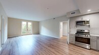 Located at 111 N Madison Ave in Pasadena, CA, this well-appointed 2-bedroom, 2-bathroom residence offers a thoughtfully designed single-floor layout. The open-concept living and kitchen area serves as the heart of the home, featuring light hardwood-style flooring that extends throughout the main living spaces, creating a bright and cohesive feel. The kitchen is outfitted with stainless steel appliances including a gas range and over-the-range microwave, grey shaker-style cabinetry, white quartz countertops, and a classic white subway tile backsplash. A set of French doors in the living area floods the space with natural light and provides direct access to an outdoor area with views of surrounding greenery. The primary bedroom is a generously sized retreat with hardwood-style flooring and French doors that further connect the interior to the outdoors. The second bedroom features plush carpeting and a window offering natural light and outdoor views, along with a built-in closet. Both bathrooms are finished with large-format tile flooring, white vanities with quartz countertops, and framed mirrors. One bathroom conveniently houses an in-unit washer. The hallway and entrance complete this clean, modern layout designed for comfortable everyday living.