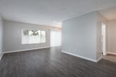 Located at 2951 E Jackson Ave in Anaheim, California, this single-story space presents a clean, updated interior with a consistent design aesthetic throughout. The layout flows logically from the living areas to the kitchen and beyond, as illustrated by the 3D floor plan overview.

The main living area is bright and welcoming, featuring durable wood-look flooring in a warm tone, neutral gray walls, and a textured ceiling. A ceiling fan with a light fixture anchors the space, while large windows with vertical and horizontal blinds allow generous natural light to filter in, creating an airy atmosphere.

The kitchen is efficiently designed in a galley configuration, outfitted with crisp white cabinetry, brushed gold hardware, white countertops, a stainless steel double-basin sink, and a gas range with a built-in microwave. Light-toned flooring complements the overall brightness of the space.

The bathroom features a wide vanity with an integrated sink, white cabinetry, and a mirrored wall, with a separate water closet housing a tub-shower combination. Additional rooms include well-proportioned bedrooms with wood-look flooring, neutral walls, windows providing outdoor views, and ample closet space, contributing to a functional and cohesive living environment.