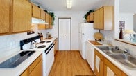 Located at 1302 Hemmingway Dr. in Fairborn, Ohio, this two-story home offers a functional and well-organized layout across two levels connected by a carpeted staircase. The galley-style kitchen is outfitted with warm oak cabinetry, laminate wood flooring, white appliances including a range, dishwasher, and refrigerator, along with ample upper and lower cabinet storage and a pantry closet. The home includes multiple bedrooms, each with soft carpet flooring and natural light from multi-pane windows framed by curtains. The bedrooms vary in size, offering versatility for different uses, and feature textured ceilings throughout. A full bathroom on the upper level includes a shower-tub combination with a decorative curtain, a wooden vanity with a wide mirror, and tile flooring. A convenient half bath is also present, featuring a pedestal sink, tile flooring, and faux-finish walls, ideal for guests. The 3D model reveals a spacious open layout on the lower level with sightlines across multiple rooms. The home's warm, neutral tones and classic oak wood finishes create a cohesive and comfortable atmosphere throughout, making it a practical and inviting residence.