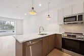 This contemporary 750 square foot apartment in Collingswood, NJ offers a harmonious blend of style and functionality. The open-concept design seamlessly integrates the living room and kitchen, creating a spacious feel enhanced by light wood flooring throughout. The gourmet kitchen boasts sleek cabinetry, stainless steel appliances, and a generous island with a white countertop, perfect for casual dining or entertaining.

The bedroom, measuring 190 square feet, provides ample space and features a large window that floods the room with natural light. The bathroom is a standout, showcasing luxurious marble-like tiling from floor to ceiling, a glass-enclosed shower, and a floating vanity that adds a touch of modern elegance.

Recessed lighting throughout the apartment complements the abundance of natural light from the large, multi-paned windows. The neutral color palette of whites and light woods creates a bright, airy ambiance that can easily accommodate various decor styles. This well-designed space maximizes every square foot, offering both comfort and style in a prime location.