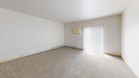 This 800-square-foot, one-bedroom, one-bathroom apartment (Unit 211) is located at 4751 46th St S in Fargo, North Dakota. The single-floor layout is designed for efficient use of space, with the open-concept kitchen and living area serving as the heart of the unit. The kitchen is well-appointed with rich dark-wood cabinetry, granite-style countertops, a central island, stainless steel appliances including a refrigerator, range, microwave, and dishwasher, and pendant lighting overhead. Light hardwood-style flooring runs throughout the kitchen, transitioning to neutral carpet in the living area. The living room is bright and open, featuring a sliding glass door with vertical blinds that allows natural light to fill the space, along with baseboard heating. The primary bedroom measures 240 square feet, offering a comfortable, carpeted retreat with a dedicated window that brings in natural light. The bathroom includes a full soaking tub and shower combination with a clean white surround. A dedicated laundry room houses a full-size washer and dryer, adding practical convenience to the unit's overall functional design.