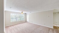 This well-designed 1-bedroom, 1-bathroom unit features a thoughtful single-floor layout that maximizes comfort and functionality. The welcoming entrance leads into a generously sized living room finished with plush wall-to-wall carpeting, crown molding, and a ceiling fan with light fixture. A large multi-pane window and a glass-paneled exterior door flood the space with natural light while providing views of the surrounding greenery. The galley-style kitchen is outfitted with white cabinetry, black appliances including a refrigerator and electric range, a double-basin sink, and wood-look flooring — offering ample counter and storage space in an efficient layout. The bedroom is a comfortable retreat, also featuring carpet flooring, a ceiling fan, and a window that brings in natural light. It includes access to a dedicated closet equipped with wire shelving and hanging rods for organized storage. The full bathroom is clean and straightforward, featuring a tub/shower combo with a curtain rod, wood-look flooring, and neutral-toned walls. Textured ceilings are found throughout the unit, and the overall neutral color palette creates a bright, cohesive atmosphere that is easy to personalize.
