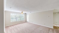 This well-designed 1-bedroom, 1-bathroom unit features a thoughtful single-floor layout that maximizes comfort and functionality. The welcoming entrance leads into a generously sized living room finished with plush wall-to-wall carpeting, crown molding, and a ceiling fan with light fixture. A large multi-pane window and a glass-paneled exterior door flood the space with natural light while providing views of the surrounding greenery. The galley-style kitchen is outfitted with white cabinetry, black appliances including a refrigerator and electric range, a double-basin sink, and wood-look flooring — offering ample counter and storage space in an efficient layout. The bedroom is a comfortable retreat, also featuring carpet flooring, a ceiling fan, and a window that brings in natural light. It includes access to a dedicated closet equipped with wire shelving and hanging rods for organized storage. The full bathroom is clean and straightforward, featuring a tub/shower combo with a curtain rod, wood-look flooring, and neutral-toned walls. Textured ceilings are found throughout the unit, and the overall neutral color palette creates a bright, cohesive atmosphere that is easy to personalize.
