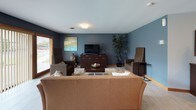 This single-floor space is thoughtfully designed with a cohesive, modern aesthetic highlighted by cool blue-grey walls, light wood trim accents, and durable tile-look flooring throughout. The open-concept living and dining area is generously sized, providing ample room for comfortable seating and a dedicated dining space. A large sliding glass door with vertical blinds floods the living area with natural light while offering direct views of a green outdoor space. Decorative artwork and tasteful furnishings contribute to the warm, inviting atmosphere of this room.

The kitchen is well-equipped and functional, featuring light maple cabinetry with brushed nickel hardware, granite-look countertops, and a full suite of stainless steel appliances including a refrigerator, electric range, over-the-range microwave, and dishwasher. The layout provides efficient workflow and ample cabinet storage. Recessed and flush-mount lighting ensures the space is well-lit throughout. Overall, the unit presents a clean, contemporary interior that balances practicality with a comfortable, livable ambiance.