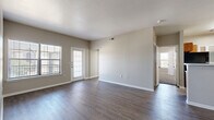 This well-appointed 4-bedroom, 2-bathroom single-story residence in San Antonio, Texas offers a practical and comfortable layout designed for everyday living. The open-concept living room is a welcoming centerpiece, featuring rich wood-style plank flooring, neutral gray walls, and multiple windows that invite abundant natural light. A glass-paneled exterior door provides additional brightness and outdoor access directly from the living area.

The kitchen is equipped with warm wood-toned cabinetry, light countertops, and black appliances including a full-size refrigerator, offering ample storage and functionality. A dedicated utility area with washer/dryer connections is conveniently accessible from the kitchen.

The four bedrooms are thoughtfully distributed throughout the home, with some featuring durable wood-style flooring and others finished with plush carpet for added comfort. The primary bedroom is generously sized and connects to a spacious walk-in closet outfitted with wire shelving systems along multiple walls, maximizing storage.

The primary bathroom is well-appointed with dual sinks, warm wood vanity cabinetry, a full tub-shower combination with tile surround, and wood-style flooring. A second bathroom serves the remaining bedrooms. Two hallways connect the layout efficiently, and the home includes one additional closet for extra storage throughout.