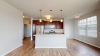 Located at 2200 Seasons Blvd in West Dundee, IL, this single-floor residence offers a clean, modern aesthetic with thoughtfully designed living spaces. The entryway welcomes you with light wood-style flooring, crisp white walls, and a gold-accented flush-mount light fixture, setting a bright and inviting tone. The open-concept kitchen and living area is a central highlight, featuring rich dark-wood cabinetry, stainless steel appliances including a refrigerator, range, and built-in microwave, complemented by light quartz countertops. A large center island with pendant lighting serves as both a workspace and gathering point, flowing seamlessly into the dining and living areas bathed in natural light from large windows with plantation-style blinds. The primary bedroom is generously proportioned with plush carpeting and an en-suite bathroom offering a glass-enclosed walk-in shower, a dark-wood vanity with quartz counters, and wood-style flooring. A spacious walk-in closet with floor-to-ceiling wire shelving and hanging rods provides exceptional storage. A secondary bathroom includes a tub-shower combination and a matching dark-wood vanity. Additional bedrooms feature soft carpeting and large windows with natural views, completing this well-appointed residence.