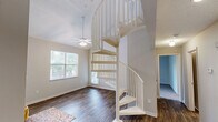 Located at 2911 Springsweet Ln in Raleigh, NC, this two-story home offers a well-organized layout across two floors. The main level provides the bulk of the living space, featuring warm hardwood-style flooring throughout. The kitchen is a standout area, equipped with white shaker cabinetry, granite countertops, a marble-style tile backsplash, a double stainless steel sink, and stainless steel appliances. Adjacent to the kitchen, the dining room benefits from a large window that invites natural light and views of surrounding greenery. A comfortable living area on the main floor features sliding glass doors that open directly onto a private balcony, extending the living space outdoors. A full bathroom on this level features granite countertops, white cabinetry, and wood-style flooring. A dedicated laundry room with full-size washer and dryer hookups and built-in shelving adds everyday convenience. Upstairs, the generously sized primary bedroom features plush carpeting, a ceiling fan, and windows allowing natural light, along with a well-appointed en-suite bathroom featuring a large vanity mirror and granite countertops. A staircase with an open railing connects both levels, enhancing the sense of openness throughout the home.