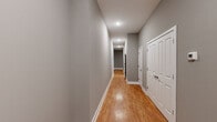 This single-floor, 3-bedroom, 2-bathroom home offers a thoughtfully designed layout with consistent, modern finishes throughout. Warm hardwood-style flooring flows seamlessly across every room, complemented by neutral gray walls and crisp white trim and doors that create a clean, cohesive aesthetic.

The combined kitchen and living area serves as the heart of the home. The kitchen is equipped with full stainless steel appliances — including a refrigerator, electric range, over-the-range microwave, and dishwasher — set against sleek gray countertops and floor-to-ceiling white shaker-style cabinetry. Track and recessed lighting illuminate the space effectively.

A long, well-lit hallway connects the bedrooms and bathrooms, maintaining the same hardwood-style flooring and neutral palette. The spacious primary bedroom offers generous room and features a ceiling fan with light fixture. The additional bedrooms are comfortably sized, with one benefiting from natural light through a window with blinds. Each room includes ceiling fans or recessed lighting for comfort.

The bathrooms are finished with white subway tile surrounds in the tub/shower combinations, accented by a decorative blue mosaic tile border, brushed nickel fixtures, and clean white fixtures throughout. A dedicated closet provides additional storage. The overall design is modern, functional, and move-in ready.