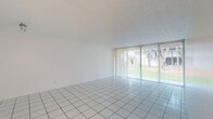 Located at 2940 Forest Hills Blvd in Coral Springs, Florida, this single-floor unit offers a clean, bright, and functional layout designed for comfortable everyday living. The main living area is generously proportioned, featuring crisp white tile flooring and a full wall of sliding glass doors dressed with vertical blinds that flood the space with natural light and provide views of the lush, green outdoor surroundings. The open layout creates a seamless flow throughout the common areas. The kitchen is efficiently designed with white cabinetry, speckled countertops, a coil-burner electric range, a built-in dishwasher, and a stainless steel sink — offering practical functionality in a tidy, well-organized space. A full-size refrigerator is also included. The bedrooms feature wall-to-wall carpeting for added comfort, with sliding glass doors or windows that continue to bring in natural light. Each bedroom includes closet space with sliding panel doors. The unit includes two bathrooms: one featuring a tub and shower combination enclosed by sliding glass doors, and a second with a standalone shower, toilet, and vanity with mirror. A dedicated hallway with built-in closet storage adds to the overall utility of this well-lit, move-in ready Coral Springs residence.