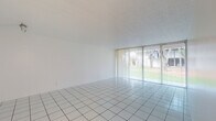 Located at 2940 Forest Hills Blvd in Coral Springs, Florida, this single-floor unit offers a clean, bright, and functional layout designed for comfortable everyday living. The main living area is generously proportioned, featuring crisp white tile flooring and a full wall of sliding glass doors dressed with vertical blinds that flood the space with natural light and provide views of the lush, green outdoor surroundings. The open layout creates a seamless flow throughout the common areas. The kitchen is efficiently designed with white cabinetry, speckled countertops, a coil-burner electric range, a built-in dishwasher, and a stainless steel sink — offering practical functionality in a tidy, well-organized space. A full-size refrigerator is also included. The bedrooms feature wall-to-wall carpeting for added comfort, with sliding glass doors or windows that continue to bring in natural light. Each bedroom includes closet space with sliding panel doors. The unit includes two bathrooms: one featuring a tub and shower combination enclosed by sliding glass doors, and a second with a standalone shower, toilet, and vanity with mirror. A dedicated hallway with built-in closet storage adds to the overall utility of this well-lit, move-in ready Coral Springs residence.