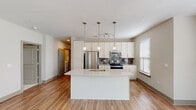 Located at 930 Jones Franklin Rd in Raleigh, NC, this single-floor residence offers a thoughtfully designed layout with a contemporary aesthetic throughout. The kitchen serves as a central highlight, showcasing white shaker cabinetry extending to the ceiling, quartz countertops, and a full suite of stainless steel appliances including a refrigerator, electric range, and over-the-range microwave. A gray subway tile backsplash adds texture and contrast, while a spacious island with an undermount sink provides additional prep space and seating. Three globe pendant lights hang above the island, complementing the track lighting above. Wood-style flooring flows through the kitchen and into the open living area, which is bright and generously proportioned, featuring multiple windows, a ceiling fan, and access to an outdoor balcony. The bedrooms are carpeted for comfort, each equipped with a ceiling fan and windows offering natural light and outdoor views. The bathroom is elegantly finished with marble-look tile flooring, an extended vanity with a light-toned countertop, chrome fixtures, and a full tub-shower combination. Neutral wall tones and consistent finishes contribute to a clean, cohesive ambiance throughout the space.