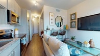 Located at 380 W 13th Ave in Denver, Colorado, this single-floor unit offers a thoughtfully arranged layout that maximizes every inch of its footprint. The open-concept living and kitchen area serves as the heart of the space, where rich hardwood-style flooring flows continuously throughout, creating a cohesive and warm aesthetic.

The kitchen is outfitted with light gray cabinetry, granite countertops, a subway tile backsplash, and stainless steel appliances including a range, microwave, and refrigerator. A gold-toned faucet adds a contemporary accent over the undermount sink. Natural light enters through a window with views of the surrounding Denver cityscape.

Adjacent to the kitchen, the living area accommodates a sofa and glass coffee table alongside a built-in granite bar ledge with bar seating — an efficient dining solution that doubles as an accent feature. A large window and sliding glass door allow ample natural light and provide access to an outdoor balcony with urban views.

The bedroom offers a quiet retreat with neutral tones, wall-mounted lighting, and framed artwork. The full bathroom features subway tile surrounding the tub-shower combination, granite vanity countertop, gray cabinetry, wood-look flooring, and a mirrored medicine cabinet, completing this functional and modern Denver residence.