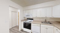 Located at 1424 Haslett Rd in East Lansing, Michigan, this single-floor unit offers a clean, functional layout with consistent light wood-tone flooring and a neutral color palette throughout. The kitchen is well-appointed with white raised-panel cabinetry extending to the ceiling for generous storage, complemented by beige laminate countertops. White appliances include an electric range, built-in microwave, dishwasher, full-size refrigerator, and a stainless steel sink — providing everything needed for day-to-day cooking. The living and bedroom areas are bright and open, benefiting from natural light streaming through vertical-blind-covered windows. The rooms feature clean white walls and textured ceilings, creating a simple, move-in-ready atmosphere. Closet space is well integrated, with sliding-door closets offering hanging storage. The bathroom is neatly finished with a white tile tub-and-shower surround, wood-look flooring, white cabinetry with matching countertops, and chrome fixtures. Throughout the unit, the consistent use of light tones and wood-look flooring lends a cohesive, tidy aesthetic well-suited for comfortable everyday living in the East Lansing area.