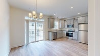 Located at 339 H St in Carlisle, PA, this three-story, five-bedroom, three-bathroom home offers a well-organized layout spread across three distinct levels. The ground floor includes an attached garage with an automatic opener and a utility room, providing practical storage and functional support spaces. The main living level features a bright, open-concept kitchen and dining area finished with light hardwood-style flooring, gray shaker cabinetry, granite countertops, stainless steel appliances, and a chandelier overhead. Large sliding glass doors connect the dining area to an outdoor patio, filling the space with natural light. A separate living room, pantry, and hallway complete this floor. The upper level houses the bedrooms, including a spacious primary bedroom with vaulted ceilings, a ceiling fan, plush carpeting, and a large window overlooking the outdoors. Additional bedrooms feature hardwood-style flooring and ceiling fans with generous natural light. Three full bathrooms, including one with a soaking tub and shower combination, serve the home's occupants. Carpeted staircases with warm wood banisters and railings connect all floors, with hallways finished in clean, light hardwood-style flooring throughout. A dedicated laundry room and four closets add to the home's practical appeal.