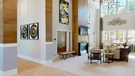 Located at 3134–3202 Sunset Blvd in West Columbia, SC, this expansive single-story clubhouse offers a generously proportioned gathering space designed with a modern aesthetic and high-end finishes throughout. The centerpiece of the space is a dramatic main lounge featuring soaring double-height ceilings clad in warm wood-paneled accent walls, a sleek linear fireplace, and curated artwork that adds visual interest at every turn. Large windows invite abundant natural light, creating an open and welcoming atmosphere. Adjacent seating areas are thoughtfully arranged, including a casual lounge with bold amber accent chairs grouped around a low coffee table, and a more refined sitting room with a neutral sofa set accented by yellow and navy throw pillows. Striking industrial-style sliding glass barn doors provide flexible division between zones. The kitchen and bar area is outfitted with dark stone countertops, a substantial central island, open shelving, a white penny-tile backsplash, built-in appliances, and a wall-mounted television — ideal for entertaining. A dedicated game room houses a full-size billiard table beneath recessed lighting. A private conference room with a long dark table, cane-back chairs, and a sculptural pendant light completes the offering, making this clubhouse equally suited for social gatherings and professional meetings.