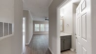 This single-floor residence offers a thoughtfully designed layout with consistent, modern finishes throughout. Light-toned hardwood-style flooring flows seamlessly across the living areas, bedrooms, and hallways, creating a cohesive and clean aesthetic. Crown molding accents the main living area, which features a ceiling fan and generous wall space suited for a variety of furniture arrangements.

The kitchen is a standout feature, showcasing grey shaker-style cabinetry, white quartz countertops, a marble-inspired tile backsplash, and a full suite of stainless steel appliances including a refrigerator, range, and over-the-range microwave.

The sunlit living and dining areas benefit from multiple large windows dressed with horizontal blinds, framing lush, tree-lined views and filling the space with natural light. A dedicated sunroom or flex area further enhances the sense of openness with wraparound windows.

The bathroom is finished with matching grey cabinetry, a white quartz vanity top, a framed mirror, and a tiled tub-shower combination. Additional bedrooms are well-sized with ample closet access and continue the light flooring palette.

Completing the unit is a dedicated in-unit laundry area with a full-size top-loading washer and dryer, adding everyday convenience to this well-rounded residence.