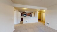 Located at 7410 South Hayford Road in Spokane, WA, unit B201 is a thoughtfully laid-out single-floor residence that combines functionality with a clean, neutral aesthetic throughout. The open-concept living and dining area is finished with plush carpeting and flows seamlessly into the kitchen, which features rich dark cherry cabinetry, light stone-look countertops, and a full suite of black appliances including a range, over-the-range microwave, and refrigerator. A half-wall peninsula separates the kitchen from the living space, providing both a visual boundary and additional counter space. Light wood-look flooring runs through the kitchen and utility areas, offering a practical contrast to the carpeted living and sleeping spaces. The unit includes a dedicated laundry room with a full-size washer and dryer, conveniently accessible from the kitchen area. The bedrooms are generously sized with soft carpeting and ample closet access, while the bathroom features a full soaking tub and shower combo with clean white surrounds, a dark wood vanity, and light countertops. Neutral warm-toned walls throughout create a bright, cohesive interior that is easy to personalize.