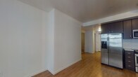 Located on the fifth floor at 1525 SW 11th Ave in Portland's vibrant SW neighborhood, this contemporary apartment offers a thoughtfully designed single-level layout with clean, modern finishes throughout. The open living area is anchored by warm hardwood-style flooring and crisp white walls, with a large window that invites natural light and views of the surrounding cityscape. A wall-mounted HVAC unit ensures year-round comfort.

The kitchen is well-appointed with dark espresso cabinetry, light quartz countertops, and a striking herringbone-pattern tile backsplash. Stainless steel appliances — including a range, over-the-range microwave, dishwasher, and a full-size refrigerator with an in-door water and ice dispenser — provide a complete, functional cooking space. An additional kitchenette area with a sink and upper cabinetry offers extra storage and prep space.

The bathroom features a combination tub and shower with a curtain enclosure, a dark-cabinet vanity with an integrated sink, and a separate walk-in shower stall with a glass door and built-in bench — a practical and accessible feature. Light tile-style flooring and chrome fixtures complete the clean aesthetic. The overall ambiance of the unit is modern, neutral, and move-in ready.