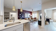 This well-appointed 2-bedroom, 2-bathroom residence offers a thoughtfully designed single-floor layout that maximizes both functionality and style. The open-concept living area is anchored by a striking deep burgundy accent wall, light wood-style flooring, and large windows that invite generous natural light. A ceiling fan adds to the comfort of the living room, which flows seamlessly into the dining and kitchen areas.

The kitchen is outfitted with stainless steel appliances including a side-by-side refrigerator and dishwasher, gray shaker-style cabinetry with gold hardware, a white quartz island with an undermount sink, and pendant lighting in a warm gold finish. The dining area features a built-in niche for additional storage and display, complemented by the same bold accent wall that carries through the space.

The primary bedroom offers a calm, neutral palette with soft tones, light flooring, and a dedicated closet. The second bedroom features a bold patterned accent wall, adding personality and visual interest. Both bathrooms are finished with clean white surfaces; one includes a soaking tub with marble-style surround. A hallway connects the bedrooms and provides additional closet storage, rounding out this complete and cohesive residence.