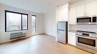 Located at 4603 Minnehaha Ave in the vibrant Longfellow neighborhood of Minneapolis, Unit 207 is a thoughtfully designed single-floor residence that maximizes its compact footprint with a clean, modern aesthetic throughout. Light wood-tone flooring runs continuously across the space, complementing the crisp white walls and creating a bright, cohesive atmosphere.

The kitchen is a functional highlight, featuring white cabinetry with ample upper and lower storage, gray countertops, a subway tile backsplash, and a warm wood-toned open shelving accent. Stainless steel appliances — including a range, dishwasher, microwave, and refrigerator — complete the well-appointed cooking space.

The open living area is bathed in natural light from large, floor-to-ceiling style windows that frame outdoor views of the surrounding neighborhood. The space offers a flexible layout suitable for both lounging and dining arrangements.

A narrow hallway connects the living areas to the bathroom, which is equipped with a glass-door stand-up shower with brushed nickel fixtures, a built-in open shelving unit for storage, a toilet, and a vanity. Recessed ceiling lighting throughout adds to the clean, well-lit ambiance of the unit.

Overall, Unit 207 presents a modern, minimalist living environment ideal for those seeking a streamlined and efficiently designed urban residence in Minneapolis.