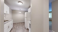 This well-laid-out one-bedroom, one-bathroom unit offers a comfortable and functional living space across a single floor. The kitchen is efficiently designed with white cabinetry, a full-size refrigerator, and a range, all complemented by wood-style plank flooring that extends into the adjacent dining area. A pendant light fixture hangs above the dining space, adding a touch of warmth. A textured ceiling and flush-mount lighting complete the kitchen area.

The spacious living room features neutral-toned carpet, a baseboard heating system, and a wall-mounted air conditioning unit, ensuring year-round comfort. A large window invites natural light and provides pleasant views of surrounding greenery, contributing to an airy atmosphere.

The bedroom is a comfortable, well-proportioned room with soft carpeting, a ceiling fan with light kit, and a window overlooking mature trees. Baseboard heating keeps the room warm, and the neutral wall tones create a calm, restful environment.

The full bathroom is clean and bright, featuring white square tile surrounding the tub-shower combination, wood-style flooring, a large mirror, and a vanity with a granite-style countertop, offering both style and practicality. Hallways connect the rooms efficiently, rounding out this practical and inviting space.