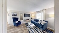 This 2-bedroom, 1-bathroom residence offers a functional and stylish single-floor layout with a cohesive neutral color palette throughout. The living room features wood-style flooring, a wall-mounted electric fireplace, and a large window that fills the space with natural light — creating a warm and inviting atmosphere. The adjacent dining area is defined by a pendant chandelier, a sliding glass door for additional natural light, and seamless access to the pass-through kitchen counter, which opens into a galley-style kitchen equipped with a full-size refrigerator and ample cabinetry. Both bedrooms are carpeted and generously sized, each offering dedicated closet space. The primary bedroom is notably spacious, featuring a walk-in closet and room for a full bedroom suite. The second bedroom also includes a closet and a bright window with curtain treatments. The shared full bathroom is clean and straightforward, featuring a full tub-shower combination with white tile surround. Two closets throughout the unit provide practical storage solutions. The overall design is light and neutral, with textured ceilings and consistent trim work tying the space together cohesively.