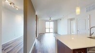 This contemporary 760 square foot apartment in Austin, TX offers a blend of style and functionality. The open-concept living area showcases a sleek kitchen with rich wood cabinetry, stainless steel appliances, and a trendy mosaic tile backsplash. A large island with a quartz countertop provides ample workspace and casual dining options.

The living room flows seamlessly from the kitchen, featuring wood-look flooring and access to a private balcony with city views. Both bedrooms are generously sized, with the primary bedroom measuring 160 square feet. They feature plush carpeting and large windows for natural light.

The bathroom boasts a modern design with a shower/tub combo, stylish vanity, and continuation of the wood-look flooring. A walk-in closet offers abundant storage space with built-in shelving and hanging rods.

Throughout the apartment, neutral tones and clean lines create a contemporary aesthetic. Ceiling fans in main living areas and bedrooms provide comfort and air circulation. The efficient layout maximizes the use of space, making this apartment feel larger than its square footage suggests.