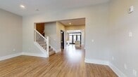 This three-story residence offers a generous 1720 square feet of living space, thoughtfully distributed across three floors. The ground level provides 320 square feet, while the first and second floors offer 730 and 670 square feet respectively. The home boasts two bedrooms, including a primary bedroom of 170 square feet, and three full bathrooms for added convenience.

The property's layout includes a well-appointed kitchen, a comfortable living room, and a hallway connecting the spaces. Storage is abundant with three closets throughout the home. Notably, the house features seven staircases, suggesting an interesting multi-level design that adds character to the interior.

The living area, as shown in the image, is particularly inviting. It features beautiful hardwood flooring that adds warmth and elegance to the space. Large windows allow ample natural light to flood the room, creating a bright and airy atmosphere. The windows also offer pleasant views of the surrounding greenery, bringing a touch of nature indoors. The room's neutral color palette, with off-white walls and trim, provides a clean, modern aesthetic that can easily accommodate various decor styles.