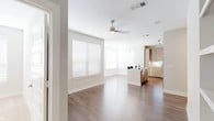 This well-appointed single-floor residence showcases a contemporary design with a neutral color palette and quality finishes throughout. The open-concept living area features rich hardwood-style flooring, a ceiling fan, and generous windows dressed with horizontal blinds that invite abundant natural light into the space.

The kitchen is a standout feature, equipped with warm wood-toned cabinetry extending to the ceiling for ample storage, stone-look countertops, a white tile backsplash, and a full suite of stainless steel appliances including a range, microwave, and refrigerator. A central island with an undermount sink and pendant lighting adds both functionality and style to the space.

The bedroom is generously sized with plush carpeting, a ceiling fan, and multiple windows that flood the room with natural light. An expansive walk-in closet connects to the bedroom, offering a well-designed built-in system with double hanging rods, open shelving, and dedicated storage cubbies.

Two bathrooms serve the residence. The primary bathroom features a long double-sink vanity with stone countertops, light wood cabinetry, bright lighting, and a glass-enclosed walk-in shower with elegant tile surround. The secondary bathroom mirrors the same refined aesthetic with a frameless glass shower enclosure, stone-topped vanity, and wood-finish upper cabinetry. Together, these spaces create a cohesive, modern living environment.