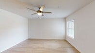 Located at 3450 Barker Cypress Rd in Houston, Texas, this single-story, 3-bedroom, 2-bathroom home offers a clean, modern design throughout. Light wood-tone flooring runs continuously across the living areas and bedrooms, creating a cohesive and bright interior aesthetic. Neutral white walls and natural light from blinds-fitted windows enhance the open, airy feel of every room.

The combined kitchen and living area serves as the heart of the home. The kitchen is outfitted with white cabinetry, marble-look countertops, a double-basin sink, and a full suite of stainless steel appliances including a refrigerator, range, microwave, and dishwasher. Track lighting overhead adds functionality to the space. A pantry provides additional storage, and a dedicated laundry area adds everyday convenience.

The primary bedroom features a ceiling fan with light, natural light from a window, and access to ample closet space. The additional bedrooms are well-proportioned, each with windows that invite natural light and outdoor views. Five closets are distributed throughout the home.

Both bathrooms echo the home's clean design, featuring white vanities with marble-look countertops, large mirrors, and light wood flooring. One bathroom includes a full tub-shower combination. A central hallway connects the living spaces to the private bedrooms and bathrooms, completing this efficiently designed home.