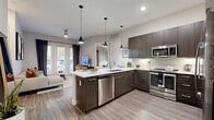 This thoughtfully designed single-floor residence offers a well-appointed layout encompassing one bedroom, two full bathrooms, a dedicated office, and two closets. The open-concept kitchen and living area serves as the heart of the home, showcasing dark espresso cabinetry, stainless steel appliances, a subway tile backsplash, and a generous white quartz peninsula with bar seating illuminated by sleek pendant lighting. Wood-look flooring runs throughout the main living spaces, lending a warm yet contemporary aesthetic. The living room is bright and inviting, featuring a glass-paned door that frames outdoor greenery and fills the space with natural light. The dedicated office provides a comfortable, carpet-floored workspace with large windows and ample room for shelving and a full desk setup. The primary bedroom is a calm retreat, highlighted by a wide window with outdoor views, soft carpeting, and convenient access to a walk-in closet with multi-rod hanging storage. The bathrooms are finished with dark cabinetry, white quartz countertops, and wood-look tile flooring, with one featuring a soaking tub and shower combination. Neutral tones, recessed lighting, and modern fixtures are consistent throughout, creating a cohesive and polished living environment.