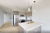 Located at 1213–1221 Broad St in Newark, NJ, this well-appointed 2-bedroom, 2-bathroom residence offers a clean, modern aesthetic throughout. Light hardwood flooring spans the entire unit, complementing the neutral gray-toned walls and crisp white trim that create a bright, airy atmosphere.

The kitchen is a standout feature, showcasing two-tone cabinetry in warm taupe with a white subway tile backsplash, quartz countertops, a central island with pendant lighting, and a full suite of stainless steel appliances including a refrigerator, range, microwave, and dishwasher — ideal for both everyday cooking and entertaining.

The bedrooms are generously proportioned, each featuring large windows dressed with navy roller shades that invite abundant natural light and offer open city and skyline views. The primary bedroom provides a comfortable, well-lit retreat.

Both bathrooms are finished with contemporary fixtures, featuring matte black hardware throughout. One bathroom includes a soaking tub with floor-to-ceiling tile surround, while the other is equipped with grab bars and a glass-enclosed shower. A dedicated laundry area houses a stacked washer and dryer unit for added convenience. The overall design is modern, functional, and move-in ready.