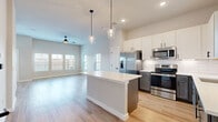 This well-appointed two-story home offers 2 bedrooms and 3 bathrooms across two thoughtfully designed floors. The main level features an open-concept kitchen and living area bathed in natural light from multiple windows. The kitchen is a standout, showcasing a large central island with a crisp white quartz countertop, two-tone cabinetry with white upper and slate-gray lower cabinets, classic subway tile backsplash, and a full suite of stainless steel appliances including a French door refrigerator, range, microwave, and dishwasher. Elegant pendant lighting hangs above the island, complementing the recessed lighting throughout. The living area features soaring ceilings, a ceiling fan, and abundant windows that fill the space with natural light. Light hardwood flooring flows seamlessly throughout both floors, adding warmth and continuity. The bedrooms are generously sized, with the primary bedroom offering notable square footage, large windows with outdoor views, and access to a closet. The bathrooms are finished with matte black fixtures and hardware, with one featuring a soaking tub and tiled surround. A convenient hallway connects the upper-floor layout, completing this clean, contemporary home.