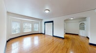 This well-appointed single-floor space showcases a cohesive and classic design throughout. Warm, polished hardwood floors extend across every room, complemented by crisp white walls and striking navy-painted baseboards and door trim that provide a clean, timeless contrast. Natural light flows generously through multiple windows fitted with horizontal blinds, creating a bright and inviting atmosphere across the living areas. Several rooms feature bay-style window arrangements, further enhancing the sense of openness and connection to the outdoors. A ceiling fan with a light fixture adds both comfort and character to one of the main rooms. A standout architectural detail is a charming arched built-in cabinet with glass panes, adding a traditional elegance to the space. The kitchen is outfitted with white cabinetry, stone-finish countertops, a subway tile backsplash, a stainless steel double sink, and a dishwasher. The bathroom retains a classic aesthetic with a black-and-white checkered tile floor, a soaking tub, pedestal-style sink, and a dark-framed mirror. A French door with glass panes adds a refined touch to the interior flow. Throughout, the space presents a balanced blend of classic character and functional design.