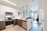 Located at 217 S Weber St in Colorado Springs, CO, this 1-bedroom, 1-bathroom unit offers a thoughtfully designed open-concept layout. The combined kitchen and living area serves as the heart of the home, featuring a peninsula island with stone countertops, two-tone cabinetry with white uppers and warm wood-toned lowers, subway tile backsplash, stainless steel appliances, and three stylish pendant lights overhead. Light wood-style flooring flows throughout, unifying the space. The living area is bright and airy, with large windows and a glass-panel balcony door that floods the room with natural light, a ceiling fan, and direct access to a private balcony with urban views. The bedroom is a serene retreat with generous natural light from oversized windows, exposed concrete architectural accents, and ample room for a full furniture arrangement. The full bathroom features light wood-look flooring, a soaking tub, a dark wood vanity, and clean white walls. Two closets provide excellent storage, while a dedicated laundry area includes a stacked washer and dryer alongside wire shelving. A utility room rounds out the functional layout of this efficiently designed Colorado Springs residence.