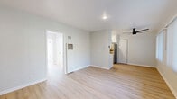 Located in the desirable West Los Angeles neighborhood of 90025, this 2-bedroom, 2-bathroom unit at 12323 Texas Ave offers a clean, modern living experience across a well-organized single-floor layout. Light wood laminate flooring runs consistently throughout, lending a bright and cohesive feel to every room.

The combined kitchen and living area serves as the heart of the unit. The galley-style kitchen is well-appointed with white shaker cabinets featuring black hardware, light quartz countertops, a deep stainless steel sink with a matte black faucet, and stainless steel appliances including a range and refrigerator. An in-unit washer and dryer are also conveniently tucked within the kitchen space.

The living room receives generous natural light through large windows dressed with vertical blinds, and is equipped with a ceiling fan. Both bedrooms are comfortably sized with neutral gray walls, light wood flooring, and windows that allow ample sunlight. The primary bedroom features a window with outdoor views.

The two bathrooms are finished in a clean, all-white palette. One includes a bathtub and shower combination with white tile surround and a high window for natural ventilation, while the other is compact and efficiently designed with built-in shelving. A connecting hallway ties all spaces together seamlessly.