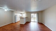 This efficient single-floor, one-bedroom, one-bathroom unit is thoughtfully laid out to maximize functionality and comfort. Rich hardwood-style flooring runs throughout the living areas, bedroom, and closet, providing a warm, cohesive aesthetic.

The open-concept living and dining area is bright and airy, anchored by a sliding glass door that leads to a private balcony offering pleasant outdoor views. A textured ceiling adds character overhead, while the layout creates a natural flow between living and kitchen spaces.

The kitchen is designed for practical use, featuring white cabinetry, a full-size refrigerator, an electric range, and a built-in microwave. A peninsula with a granite-style countertop separates the kitchen from the living area, providing additional prep space and casual seating. A window above the sink brings in natural light.

The bedroom is a comfortable, well-proportioned retreat equipped with a ceiling fan, a window with blinds for natural light and privacy, and direct access to a dedicated walk-in closet with built-in shelving and hanging rods for ample storage.

The bathroom includes a full tub-shower combination with white tile surround. The unit's neutral color palette and consistent finishes throughout create a clean, cohesive living environment.