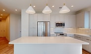 This contemporary apartment showcases a thoughtful design that maximizes space and functionality. The heart of the home is an open-concept kitchen, boasting white cabinetry, quartz countertops, and stainless steel appliances. A large island with a sink serves as both a prep area and casual dining space, illuminated by stylish pendant lights.

The bedrooms are generously sized, each featuring hardwood flooring and large windows that flood the spaces with natural light. A standout feature is the walk-in closet, offering ample storage with built-in shelving and hanging areas. The bathroom continues the modern aesthetic with a double vanity, sleek fixtures, and neutral tones.

Convenience is key in this unit, with an in-unit laundry room equipped with full-sized, front-loading washer and dryer. Throughout the apartment, the color palette is predominantly white and light wood, creating a bright, airy atmosphere. Ceiling fans in the bedrooms provide additional comfort.

The overall layout is efficient and well-planned, as evidenced by the 3D floor plan. With its combination of style, comfort, and practicality, this apartment offers a desirable living space in the heart of Tampa.